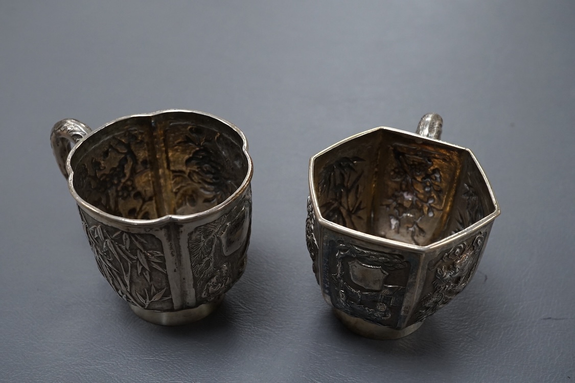 Two late 19th/early 20th century Chinese Export white metal tea cups, maker Wing Fat, embossed with bamboo, chrysanthemums and figures, of hexagonal or cusped form, 5.4oz.